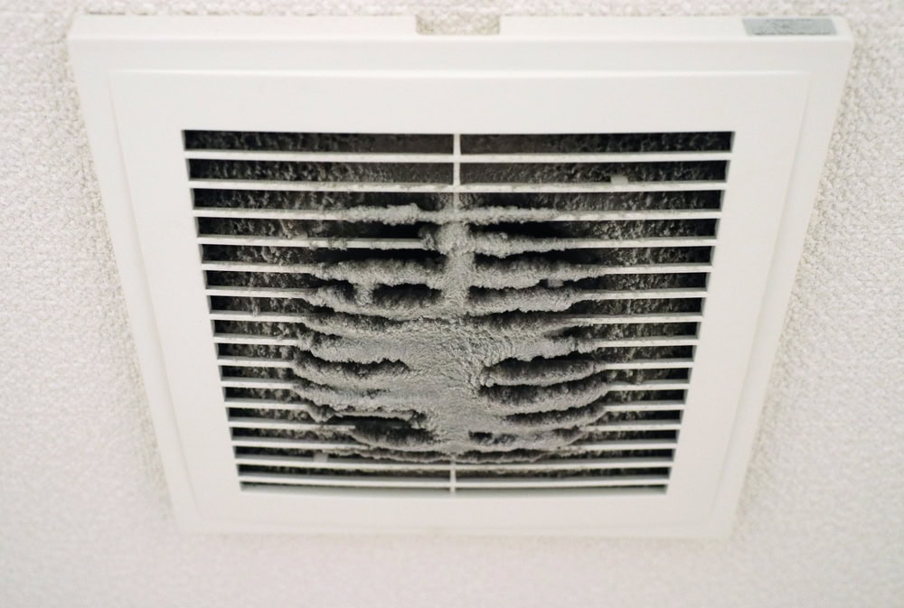 A ceiling vent covered in a thick layer of dust and debris, possibly signaling the need for professional cleaning or even Water Damage Restoration Indiana if moisture issues are present. Dust clings to the slats, creating an uneven, dirty appearance.