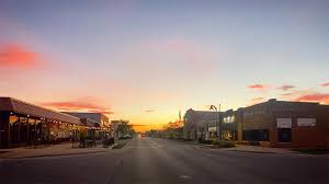 Main street in Marion County at sunset, with shops and a Damage Restoration Service under a colorful sky.