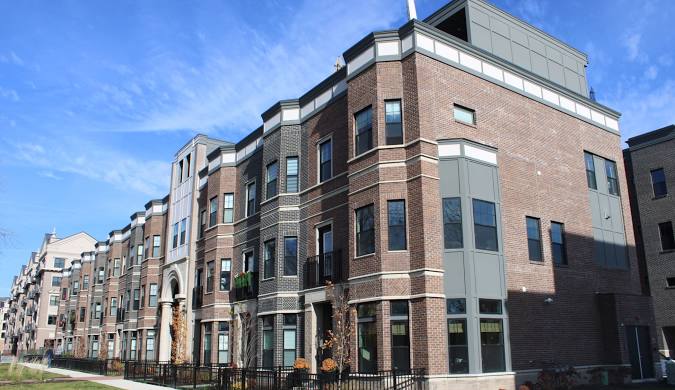 A modern brick apartment with large windows and balconies stands close to a top Damage Restoration Service.