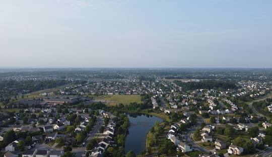 Aerial shot of a suburban neighborhood with houses, trees, and a pond in Hamilton County.
